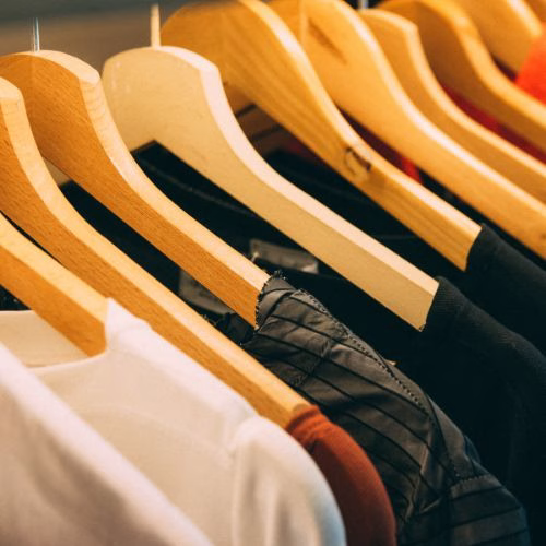 A rack of finished garments on wooden hangers in a clothing factory, ready for distribution.